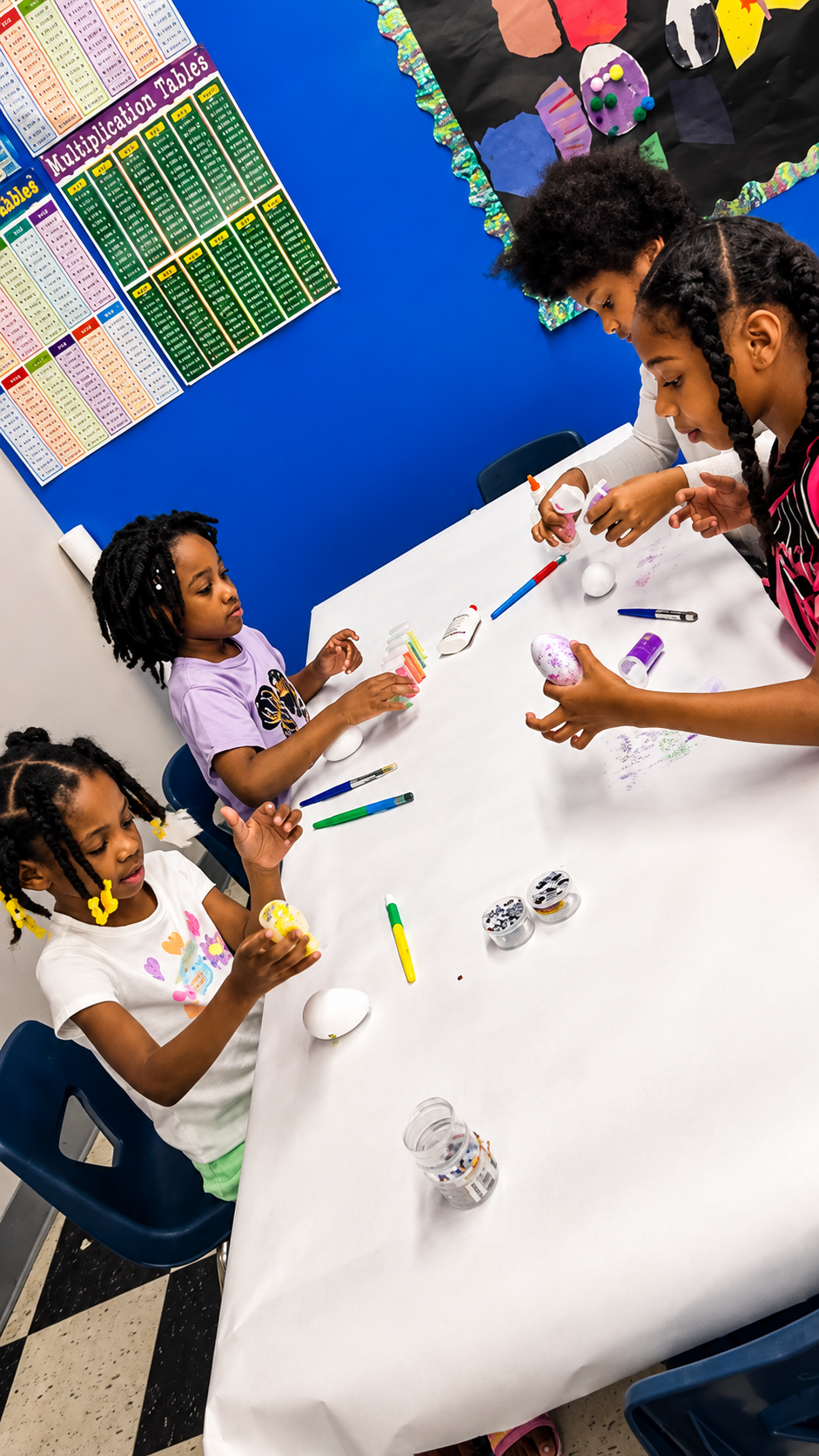 School-age children decorating crafts together at a classroom table