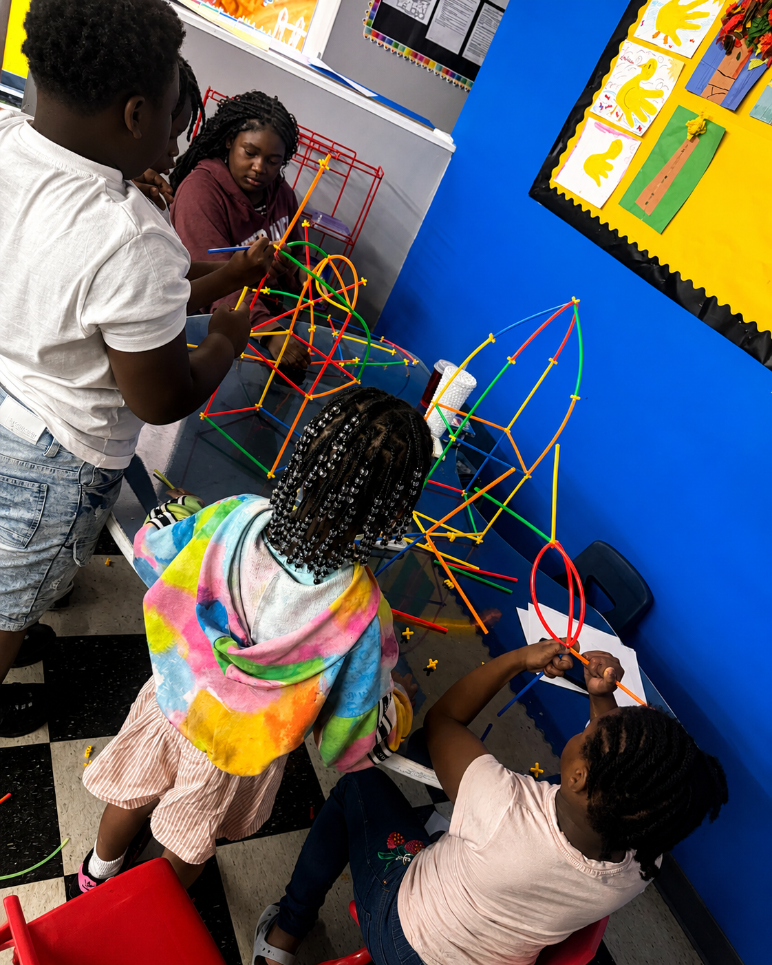 School-age children building large structures with colorful connector straws