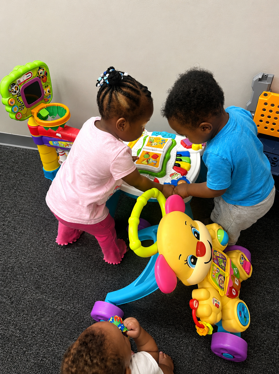 Two toddlers playing together at an activity table in the infant room