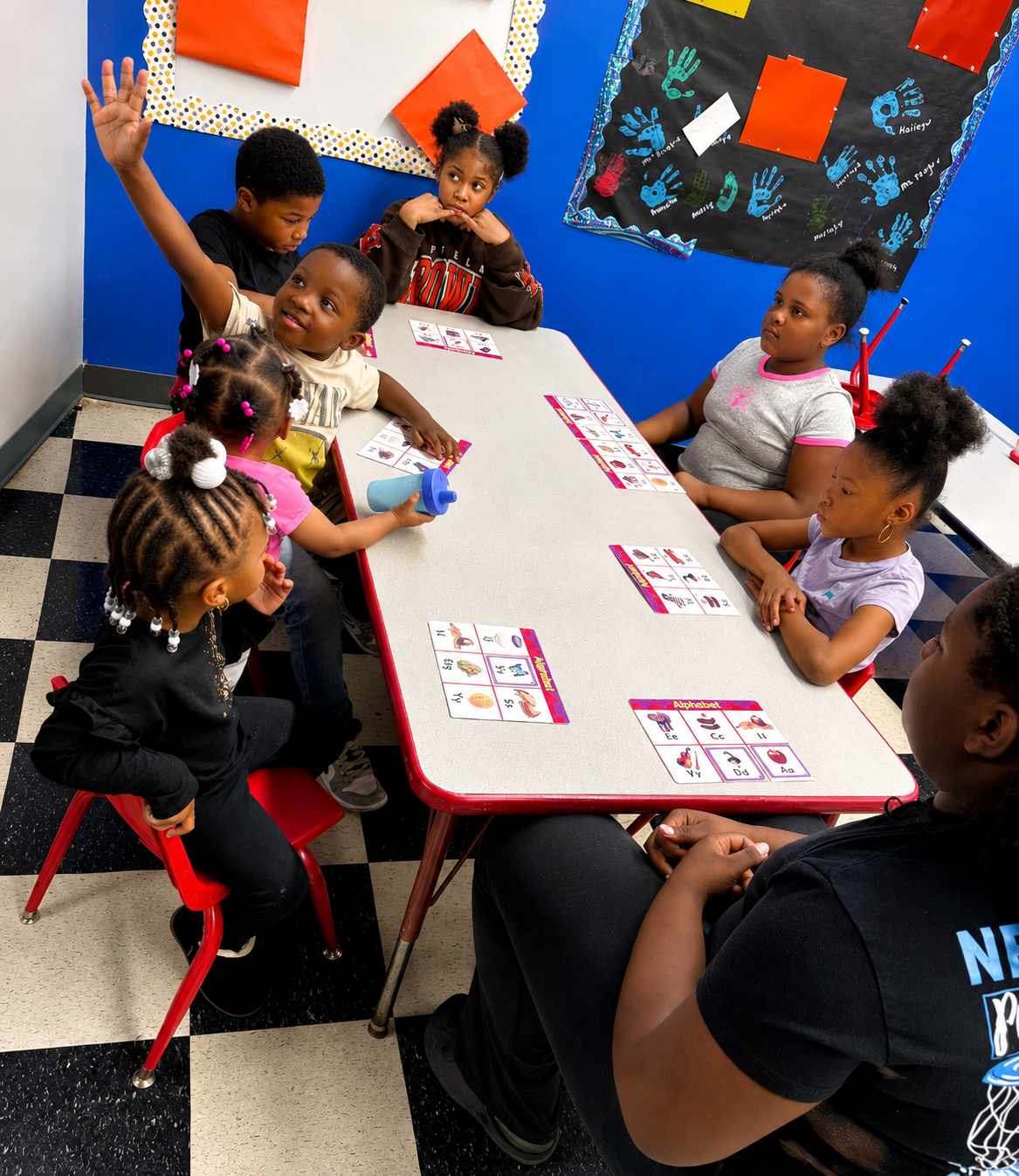 Preschoolers raising hands during an alphabet lesson with their teacher