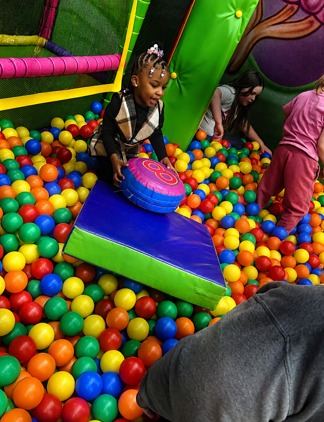 Children playing in a colorful indoor ball pit at Discovering Minds